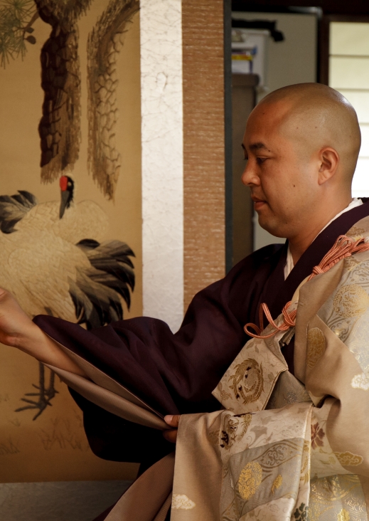 掛け軸の前で経本を持つ僧侶